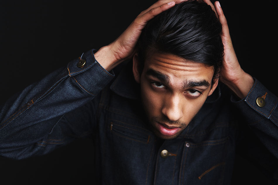 Horizontal portrait of a young man posing in denim jeans jacket with hand in hair